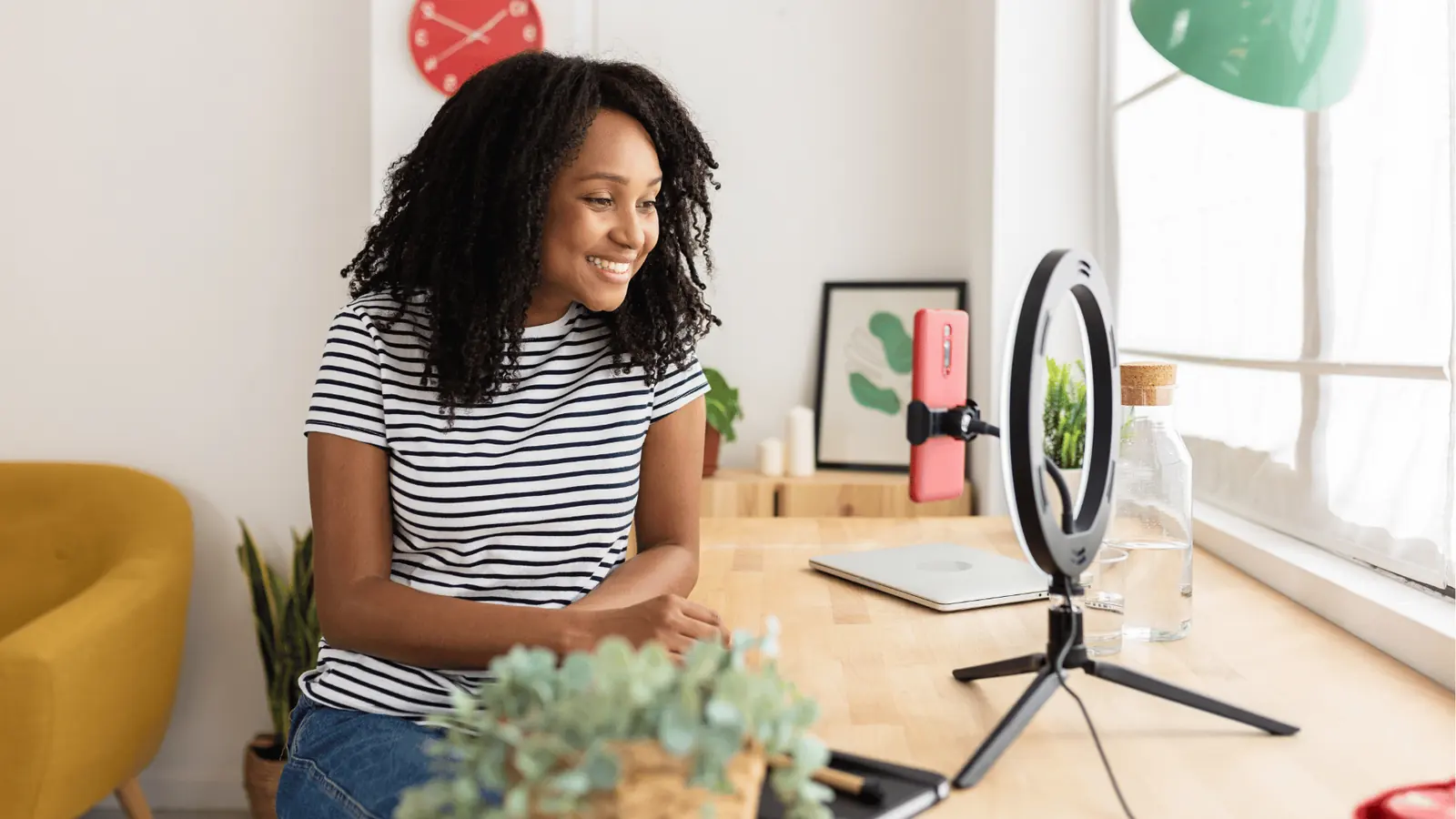Smiling woman recording video with smartphone mounted in ring light setup for inbox management