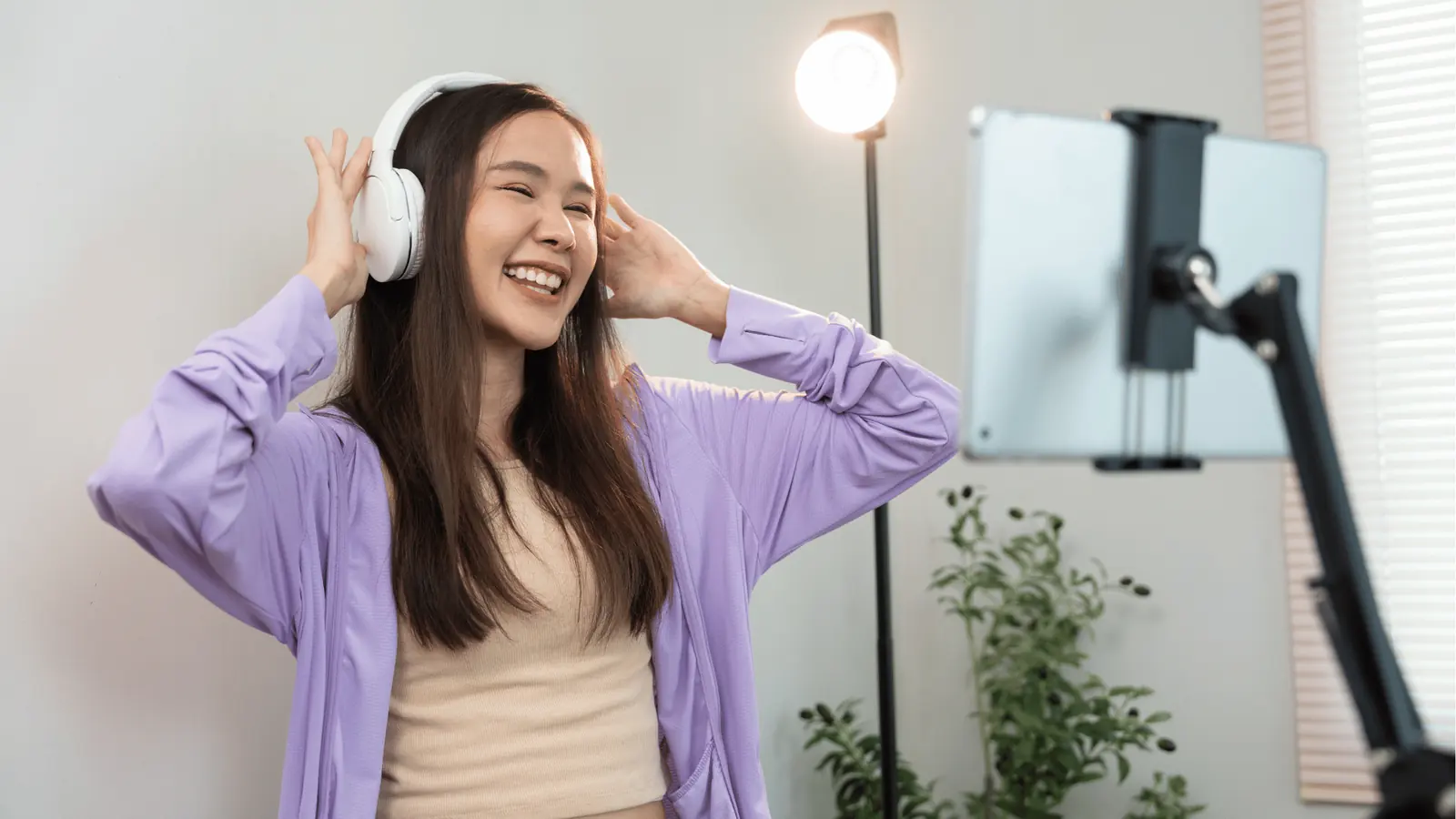 Young woman smiling wearing headphones while recording on a tablet