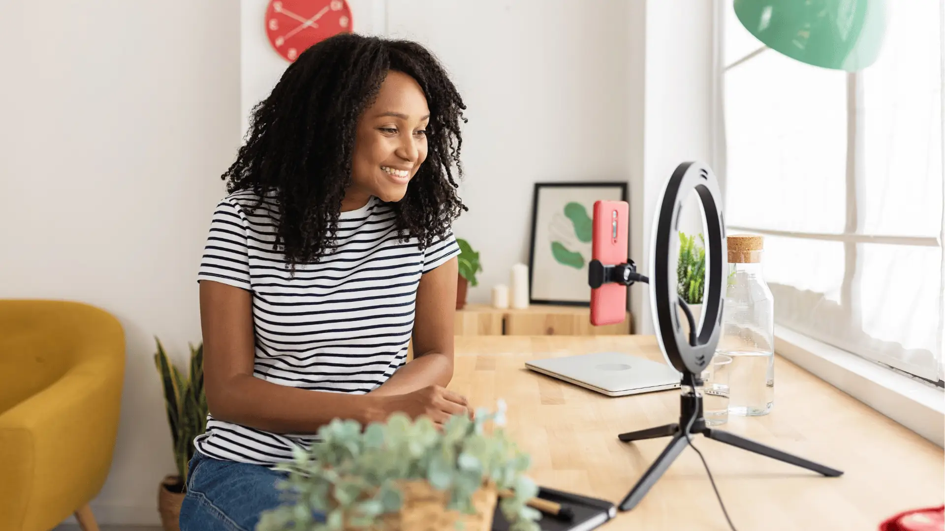 Smiling woman recording video at home desk with ring light for scheduling