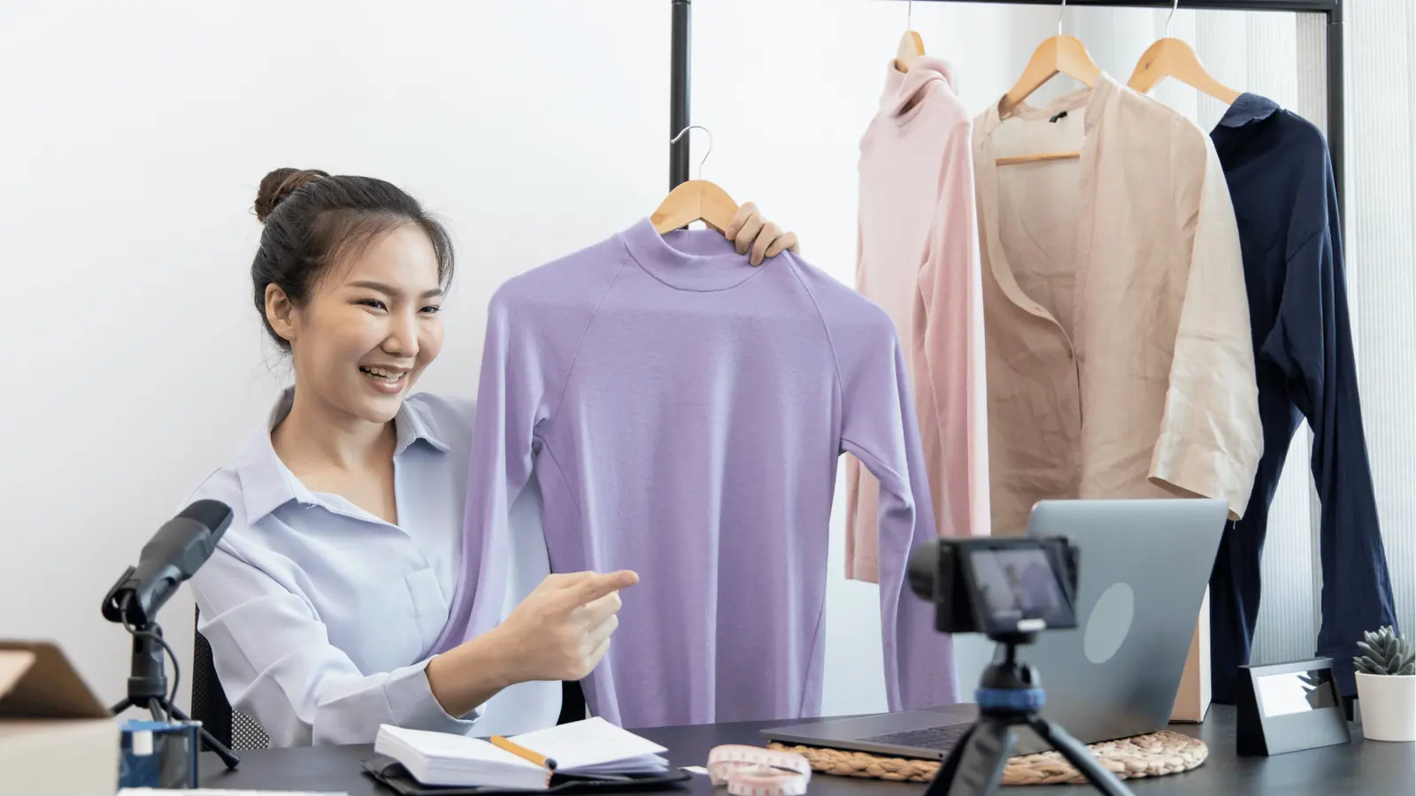 Woman on video showing a purple sweater to camera in a small studio for publishing