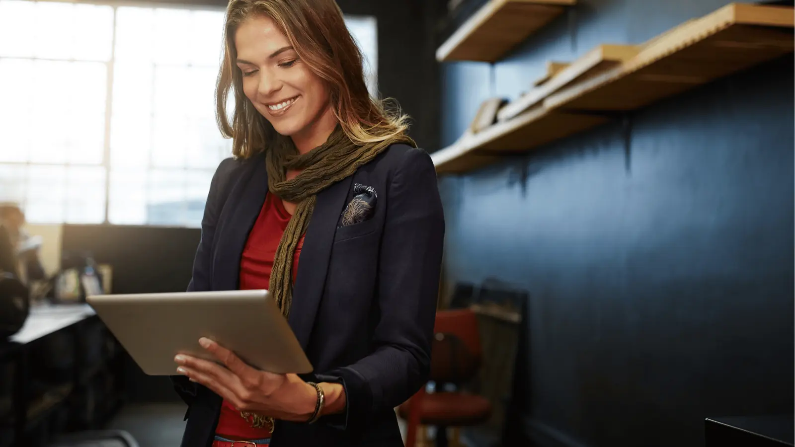 Smiling woman standing and using a tablet in a modern office