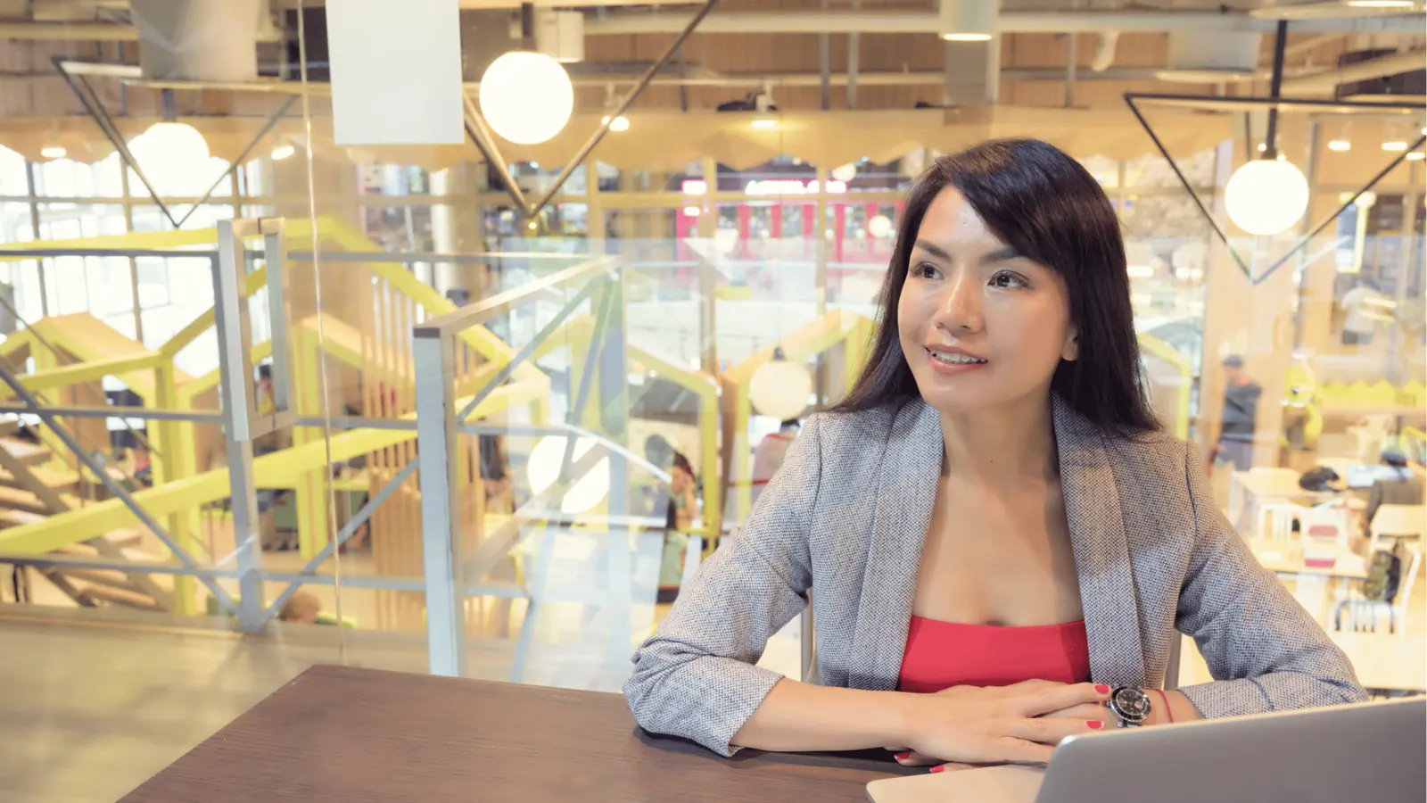 Woman sitting at a table with laptop in a bright mall cafe