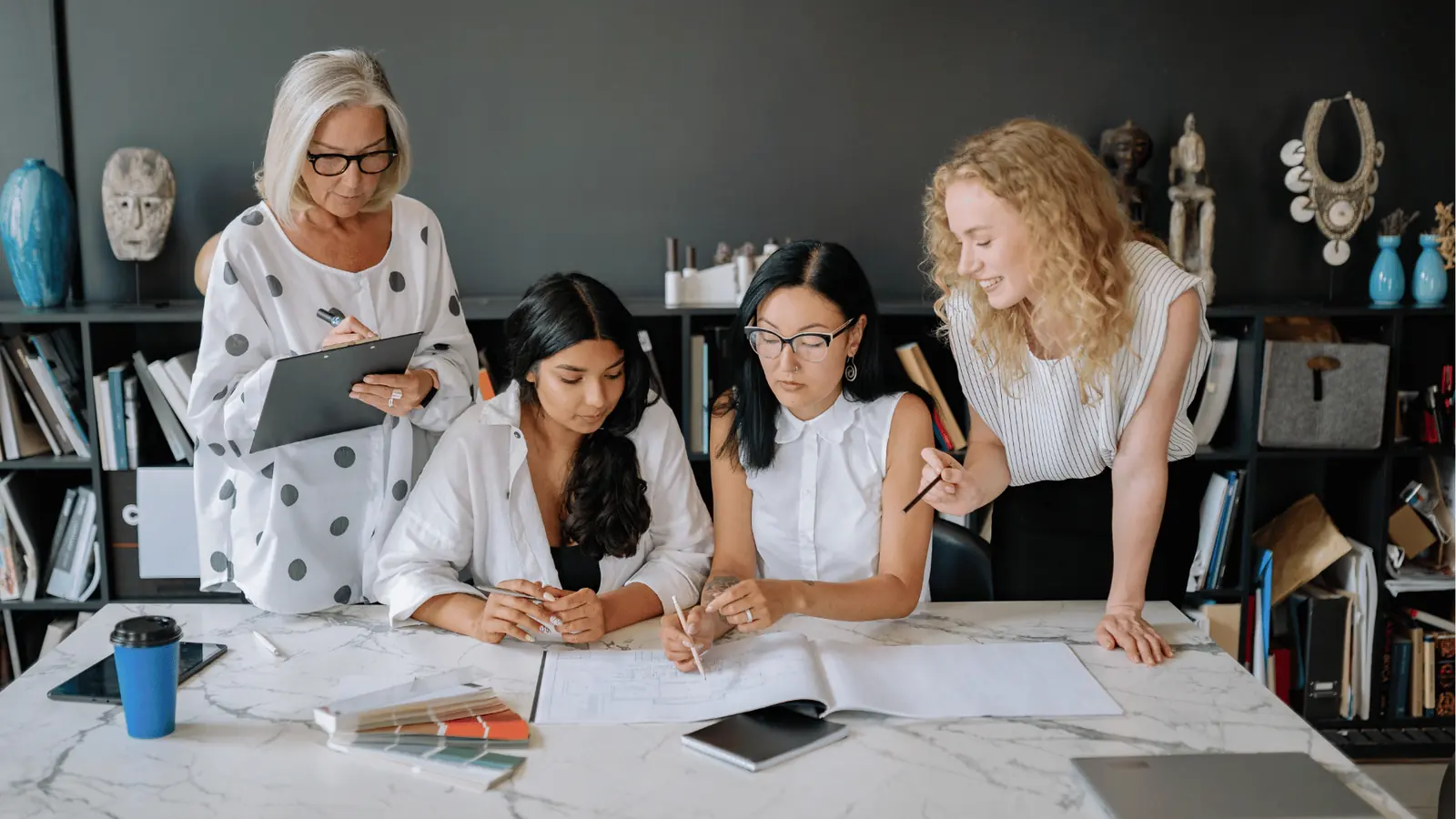Four teammates comparing content drafts and color swatches around a studio table