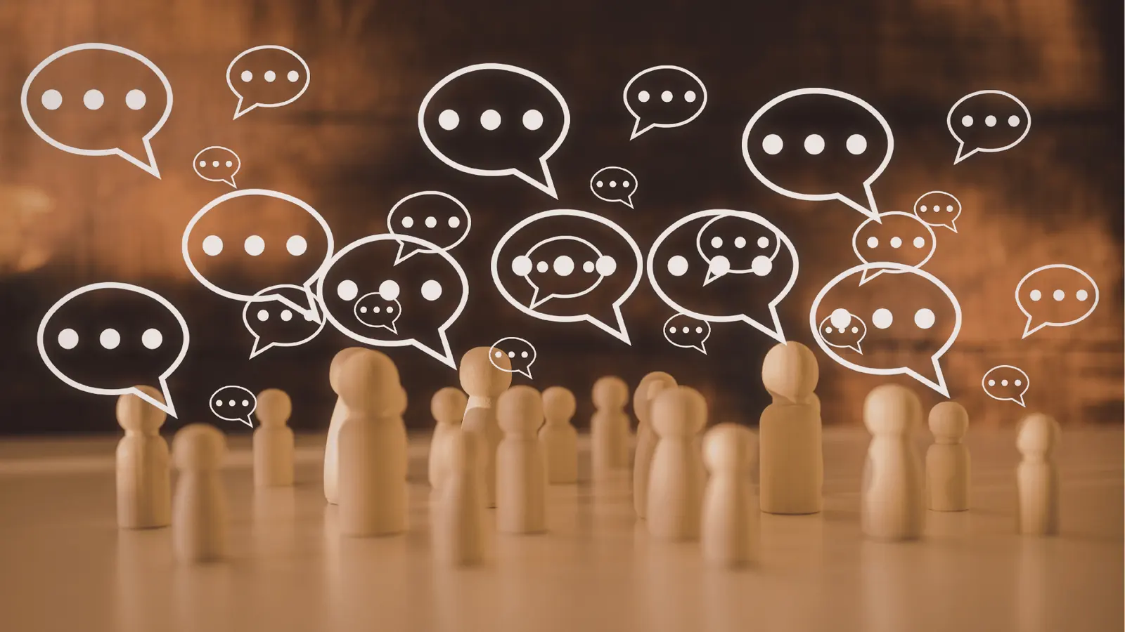 Wooden peg people with many drawn speech bubbles over blurred background for brand management