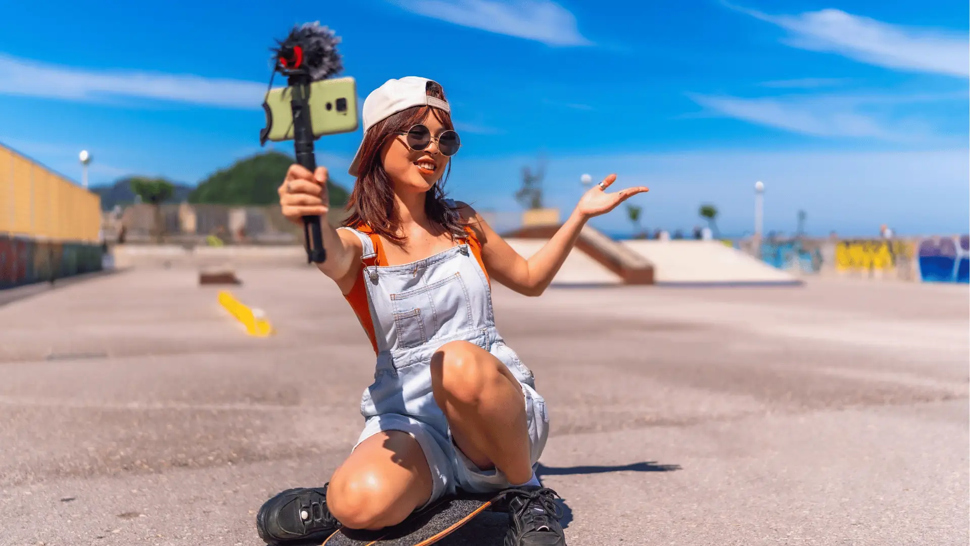 Young woman kneeling on skateboard vlogging with a smartphone mounted on a microphone for AI-assisted workflow